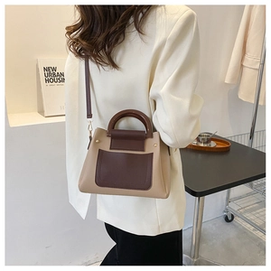 Detailed view of bicolor crossbody bag with a round wooden handle and a side outer pocket