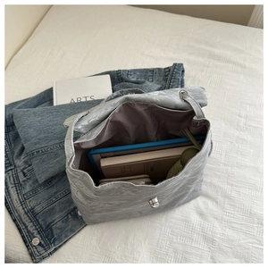 Detailed interior of a pleated silver shoulder bag showing its large storage capacity