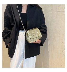Detail of a sparkling gold sequin crossbody bag with a delicate metal chain strap
