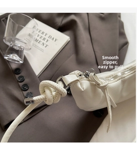 Detail of white PU leather bag with knotted shoulder strap and silver metal zipper