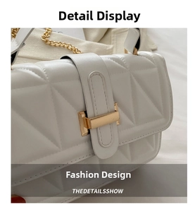 Macro shot of white quilted faux leather shoulder bag with golden clasp and chain strap