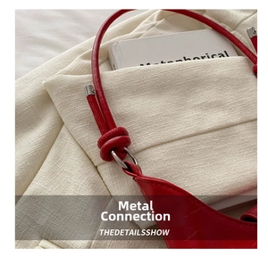 Detail of red leather handbag showing silver metal ring and rounded shoulder strap