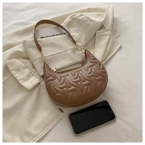 Detail view of brown crescent shoulder bag featuring geometric quilted texture and gold zipper