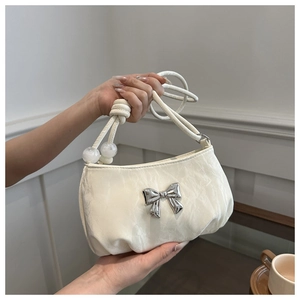 Close-up of pleated white handbag with silver metal bow and decorative knotted handle