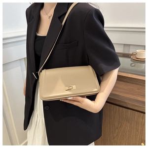 Detail of minimalist beige shoulder bag showing golden twist lock and smooth leather texture