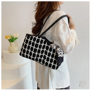 Detail of tweed tote bag with black and white grid pattern and polka dot scarf accessory