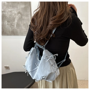 Detail of light blue bow backpack featuring lace-up side design and ruffled fabric texture