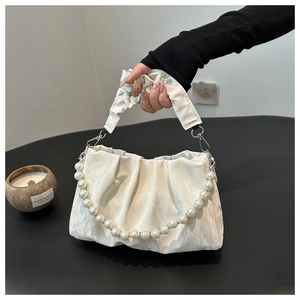 Dettaglio della catena di perle e trama a pieghe sulla borsa a nuvola bianca elegante