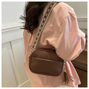 Brown leather crossbody bag detail featuring embroidered wide strap and fringe tassel charm