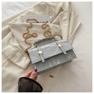 Detail of marble texture pattern on grey crossbody bag with gold chain strap and metal buckle