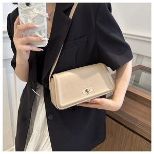 Detail of beige leather crossbody bag featuring a golden twist lock on a rectangular flap