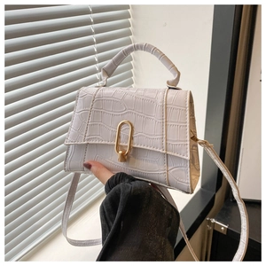 Macro detail of white crocodile-embossed leather handbag with elegant gold U-lock hardware