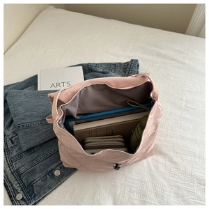 Top view of spacious pink pleated tote interior holding tablet, notebooks, and umbrella