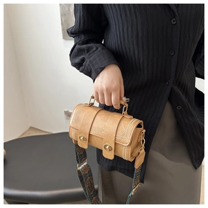Detail of vintage camel cylindrical handbag with gold locks and rivets with jacquard strap
