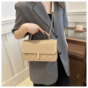 Detailansicht der beigen gesteppten Handtasche mit Goldschnalle und Kettenriemen