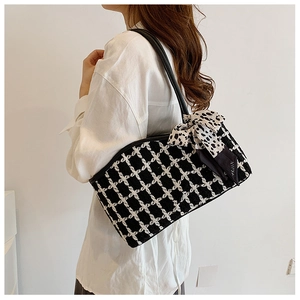 Detail of checkered hobo bag with polka dot scarf bow on shoulder strap in close-up view