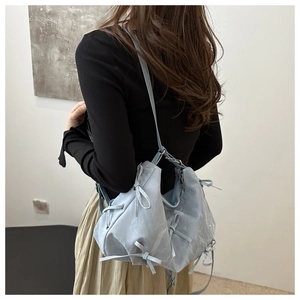 Detail of light blue bow-decorated crossbody bag with unique marble texture and metal zipper