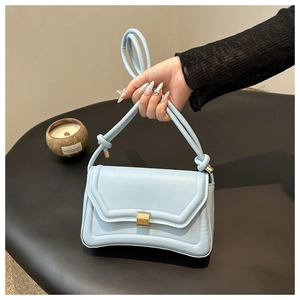 Detail showing the light blue leather handbag with a matte gold buckle and knotted handle