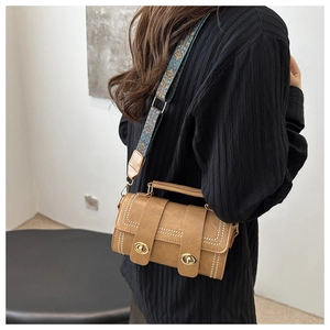 Detail of brown leather bucket bag with gold studs and bohemian pattern wide strap