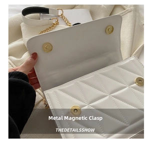 Detail shot of white quilted shoulder bag with golden magnetic snaps and chain strap