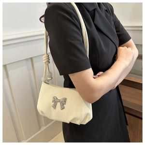 Detail of off-white ruched handbag with silver bow, beaded strap and knot accents