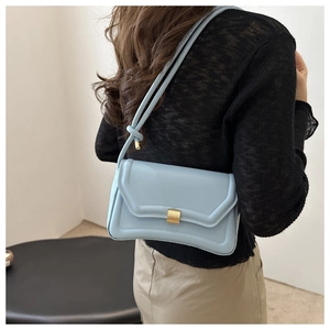 Rear view of a model wearing a light blue saddle bag with gold buckle and knot strap