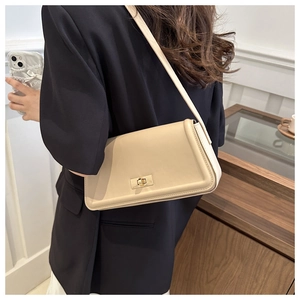 Detail of cream chain shoulder bag showing golden clasp and textured leather material