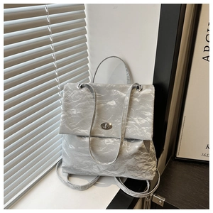 Détails de la texture métallique plissée argentée et du fermoir rotatif du sac à dos chic