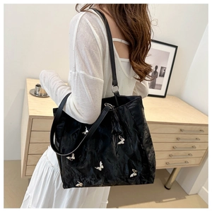 Detail shot of a black bucket bag with silver butterfly buckles and crinkled texture