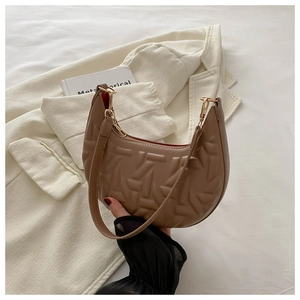 Close-up of brown crescent underarm bag with geometric embossing and gold hardware