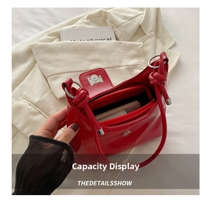 Interior view of red glossy leather shoulder bag showing zipper compartment and storage capacity