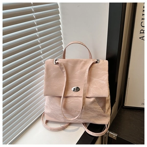 Détail d'un sac à dos rose pâle avec texture plissée et fermoir rotatif argenté au bord