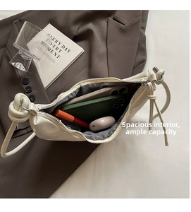 Detail of spacious ivory crescent bag interior holding phones and makeup essentials