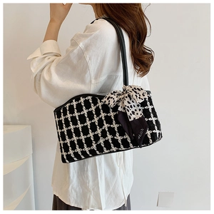 Detail of checkered tweed tote bag featuring a leather strap and leopard print bow charm