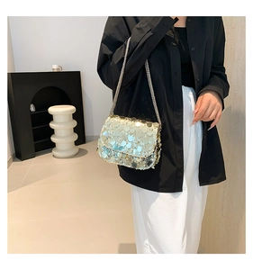 Detailed side view of fashion sequin crossbody bag with chain strap on a model