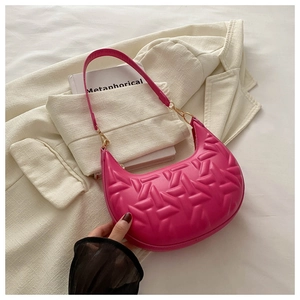 Close-up of geometric embossed rose pink crescent bag with golden hardware on a blazer
