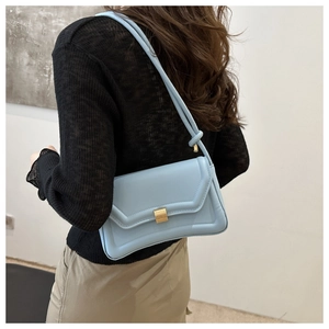 Detail of light blue saddle bag with gold buckle and knotted strap on shoulder