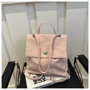 Detailed view of pale pink wrinkled texture bag with silver twist lock on leather chair