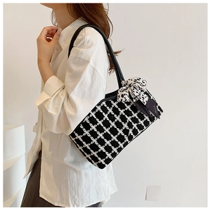 Detail of checkered tote bag with leopard print ribbon on a model's shoulder