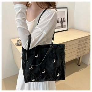 Detail of black bucket bag featuring pleated texture and silver butterfly metal studs