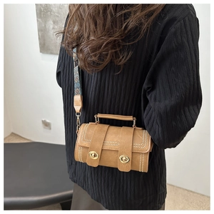 Detail view of retro cylindrical brown crossbody bag with ethnic print strap