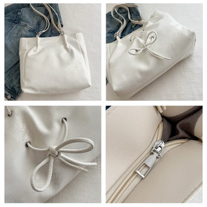 Detail view of cream tote bag featuring drawstring bow design and interior zipper pocket