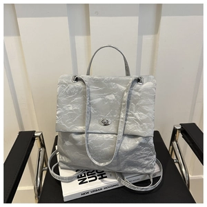 Detail of silver pleated leather texture and metallic turn-lock on soft hobo bag