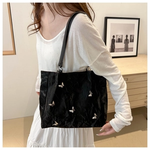 Detailed view of black pleated bucket bag with silver butterfly charms on a model