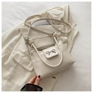 Détail de ce sac sous le bras blanc crème avec nœud en métal argenté et texture souple