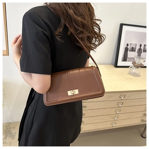 Brown leather shoulder bag with vintage gold turn-lock closure on model