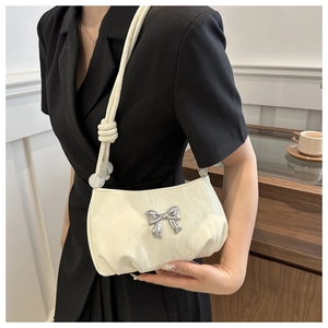 Detail of off-white pleated shoulder bag featuring a silver metal bow and braided strap