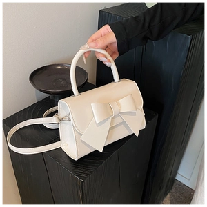 Detail of cream bow handbag showing high-quality leather texture and large bow decoration