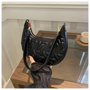 Detail of black quilted shoulder bag with 3D texture and vibrant red inner lining