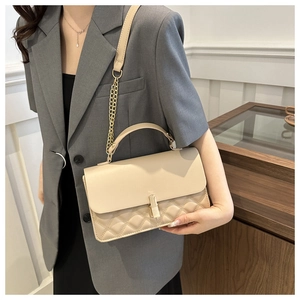 Detailansicht der beigefarbenen Stepptasche mit goldener Kette, getragen von Model